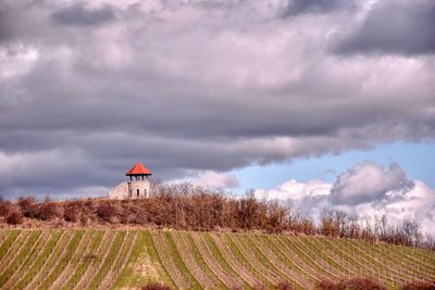 Small tower on hill against cloudy sky