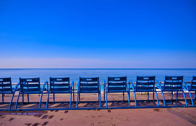 Chairs on beach against clear blue sky