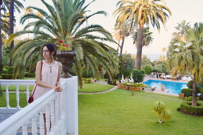 Portrait of smiling young woman with palm trees in park