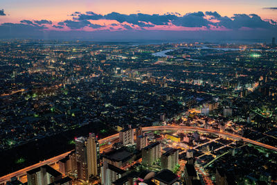 High angle view of illuminated city buildings against sky during sunset