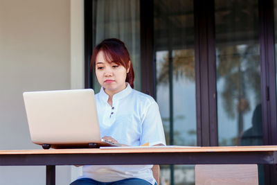 Mid adult man using mobile phone while sitting on table