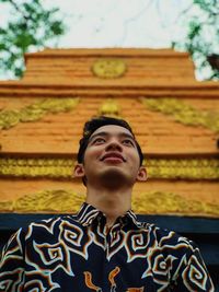 Low angle view of young man looking away while standing against temple