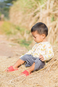 Boy sitting on dried grass