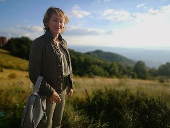 Portrait smiling woman standing on grassy field against sky