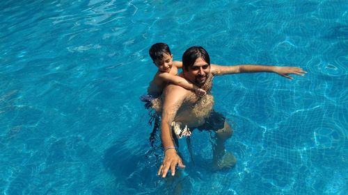 Portrait of father with son swimming in pool