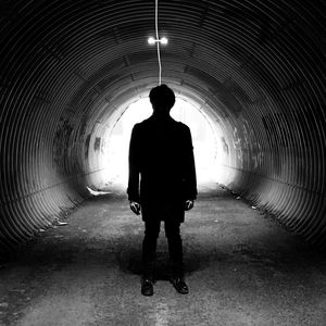 Rear view of silhouette man walking in tunnel