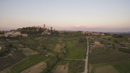 Aerial view of agricultural field in city against sky during sunset