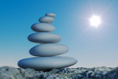 Close-up of stone stack against blue sky