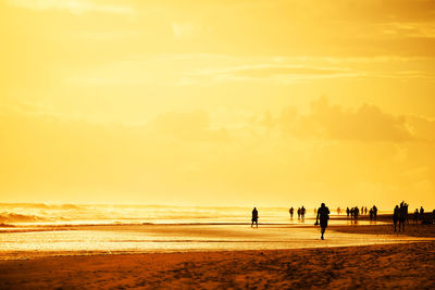 Tourists visiting beach against sky