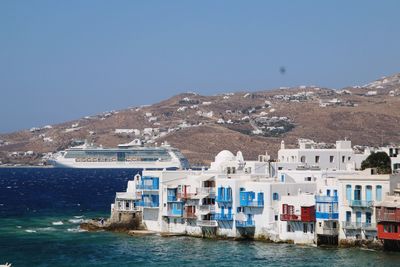 Sea by houses against clear blue sky