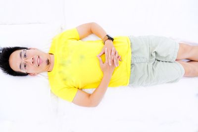 Directly above portrait of young man lying on white bed