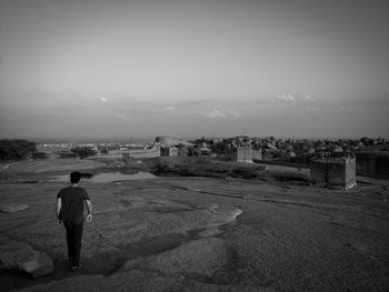 Rear view of man looking at cityscape against sky