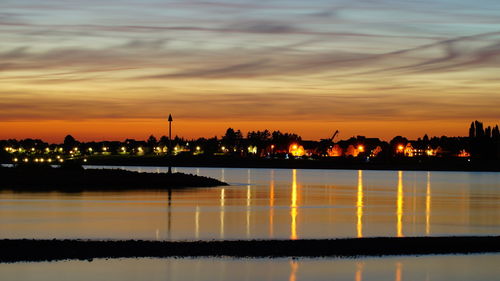 Scenic view of river against cloudy sky at sunset