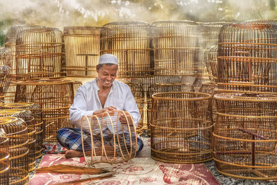 Smiling senior man making wicker baskets