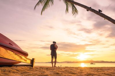 Man standing on beach against sky during sunset