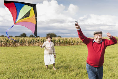 Happy senior couple flying kite in rural landscape