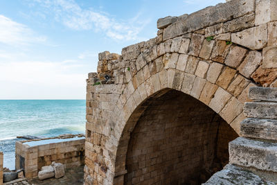 Stone wall by sea against sky