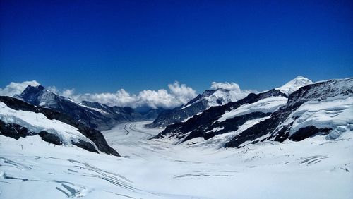 Scenic view of snowcapped mountains against blue sky