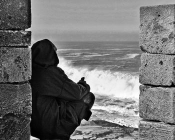 Side view of person crouching on shore