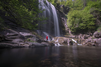 Woman looking at waterfall in forest