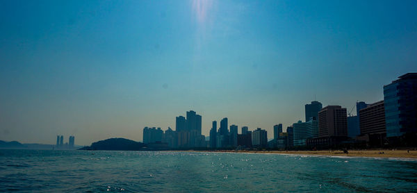 City skyline by sea against sky during sunset