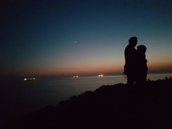 Silhouette man standing by sea against sky during sunset