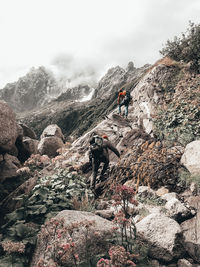 People on rock in mountains against sky