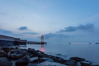 Lighthouse by sea against sky