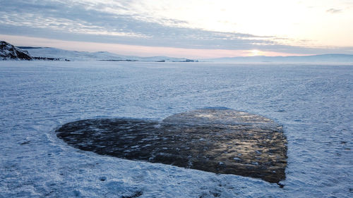 Scenic view of frozen lake against sky during sunset