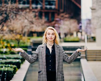 Portrait of young woman gesturing while standing outdoors