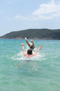 Man surfing in sea against sky