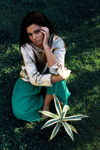 High angle portrait of young woman sitting on land in park