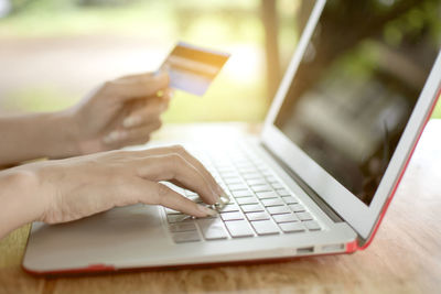 Midsection of person using laptop on table