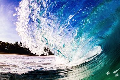 Close-up of waves splashing on beach against sky