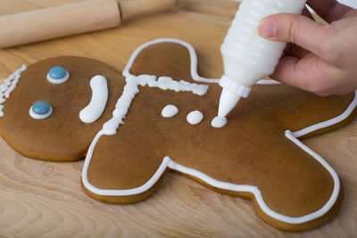 Cropped hand preparing gingerbread cookie on table