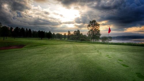 Scenic view of grassy field against cloudy sky