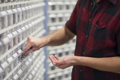 Midsection of male customer choosing nails at hardware store