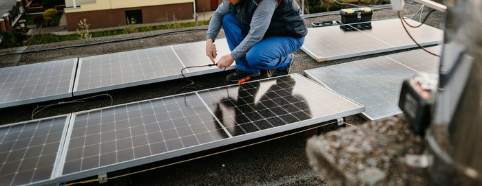 Low section of engineer inspecting solar panel