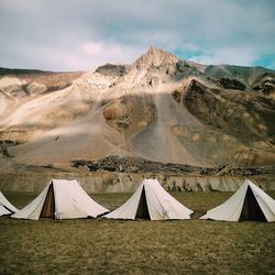 View of tents on field with mountains in background