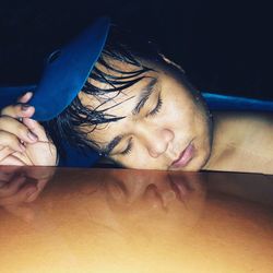 Close-up of young man with eyes closed in swimming pool at night
