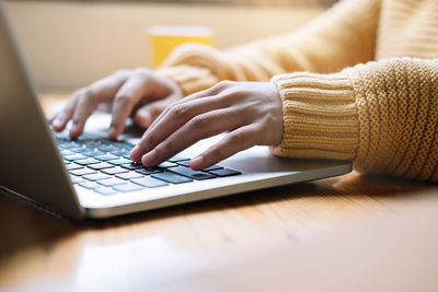 Close-up of man using laptop on table