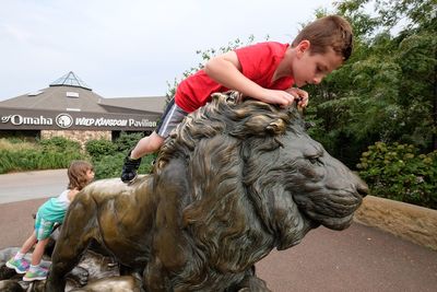 Siblings sitting on statues in park