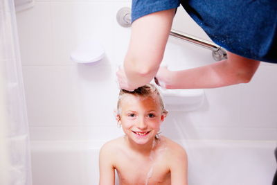 Cropped image of woman bathing son in bathtub