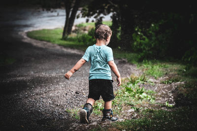 Rear view of boy standing against trees