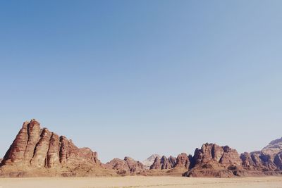 View of rock formations in desert against clear blue sky