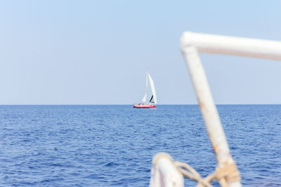 Sailboat in sea against clear sky