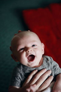 Cropped hands holding baby boy at home