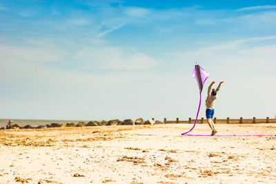 Man flying kite against sky during sunny day