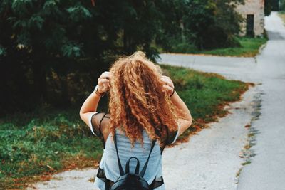 Rear view of woman with arms raised on road