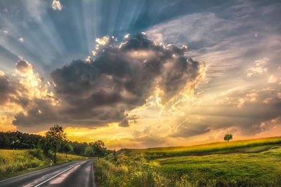 Panoramic view of road amidst field against sky during sunset